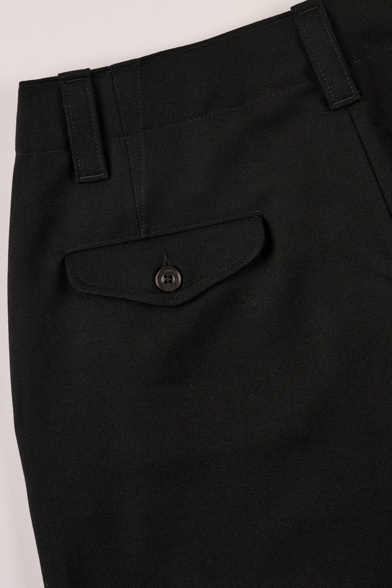 Close-up of black pants with a pocket and button