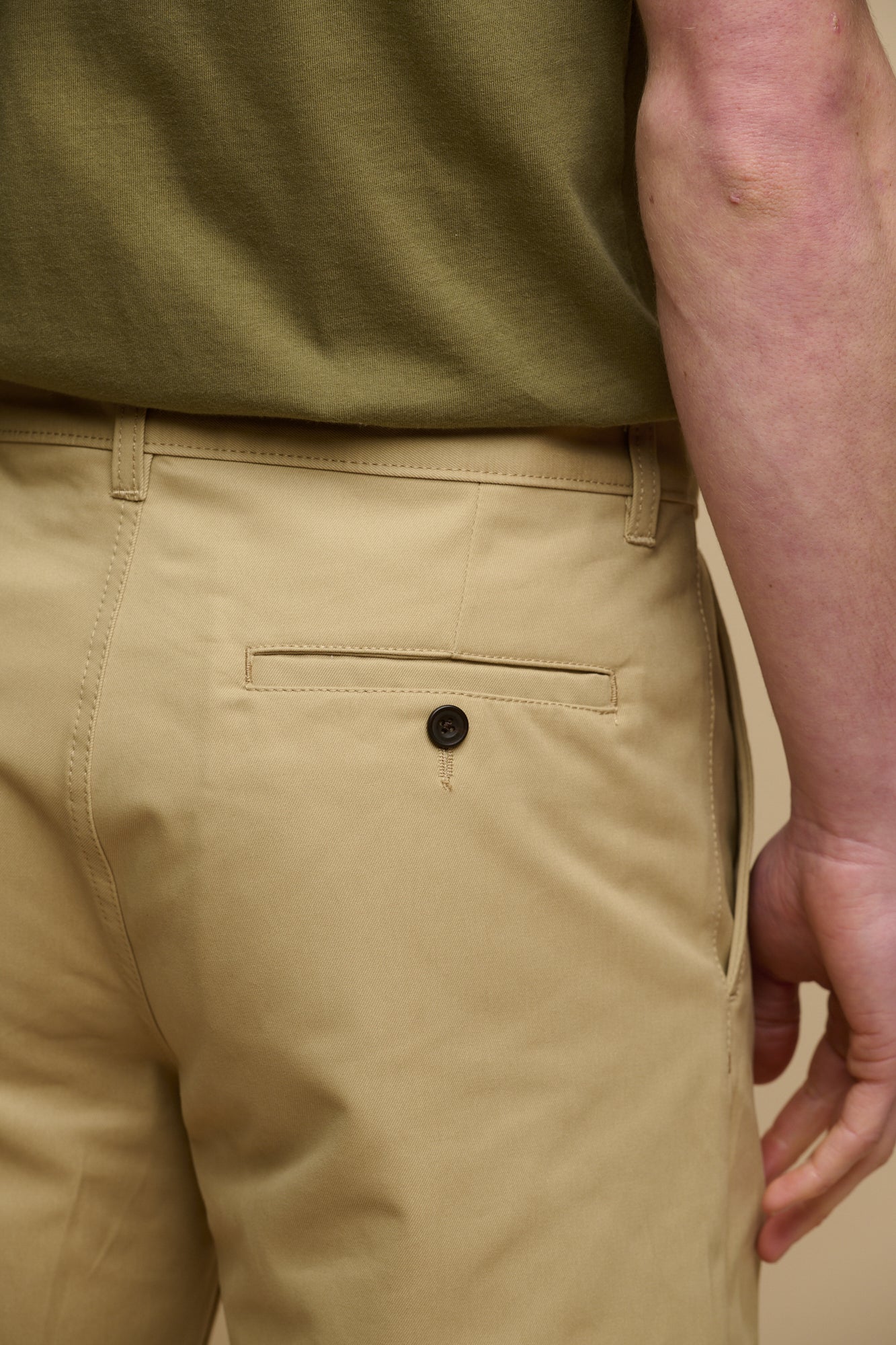 Calf up image of brunet male wearing men's classic shorts in stone with hands in front pockets