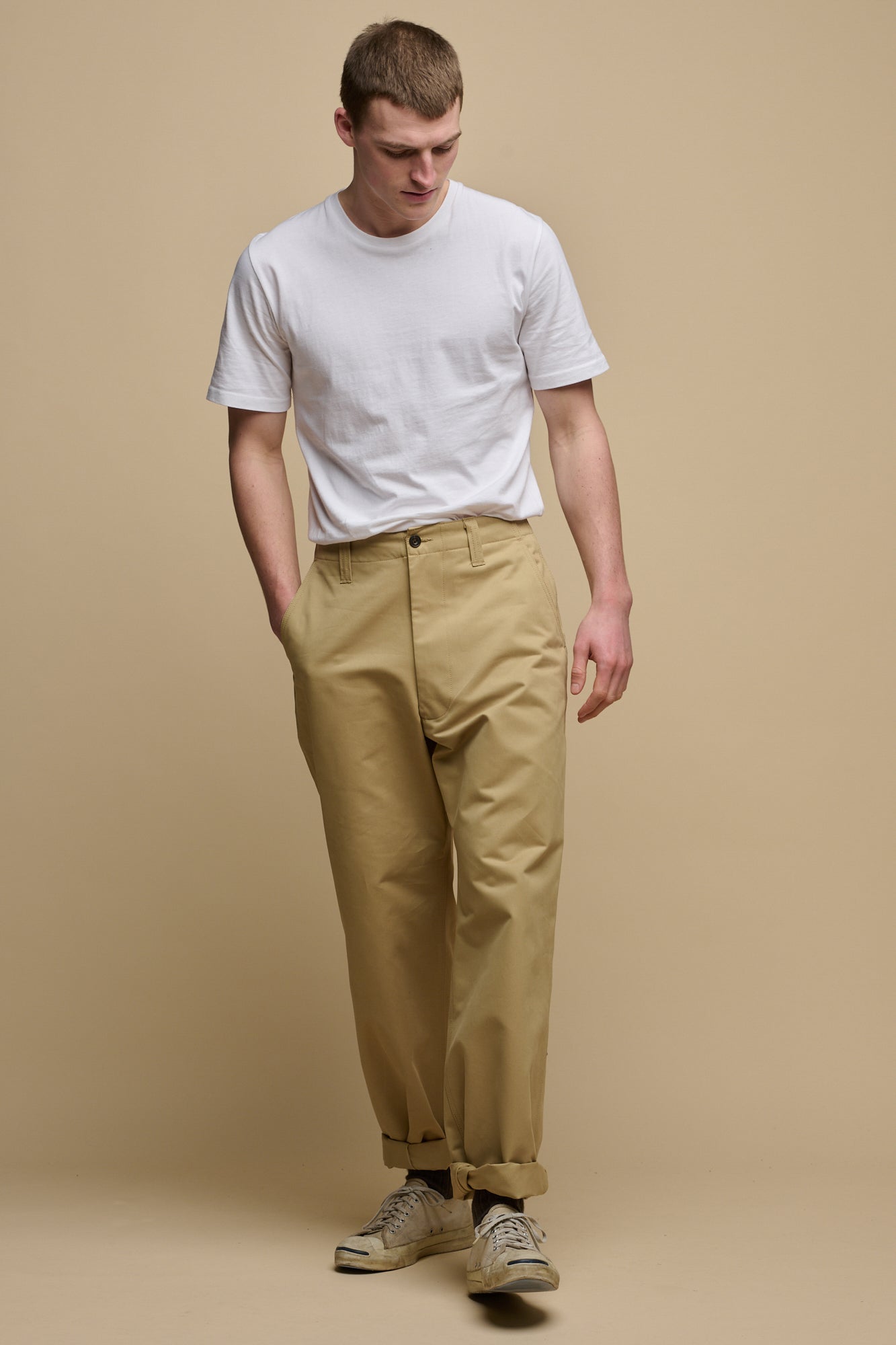 Full body image of male wearing men's field trousers in stone paired with short sleeve t shirt in white tucked into trousers
