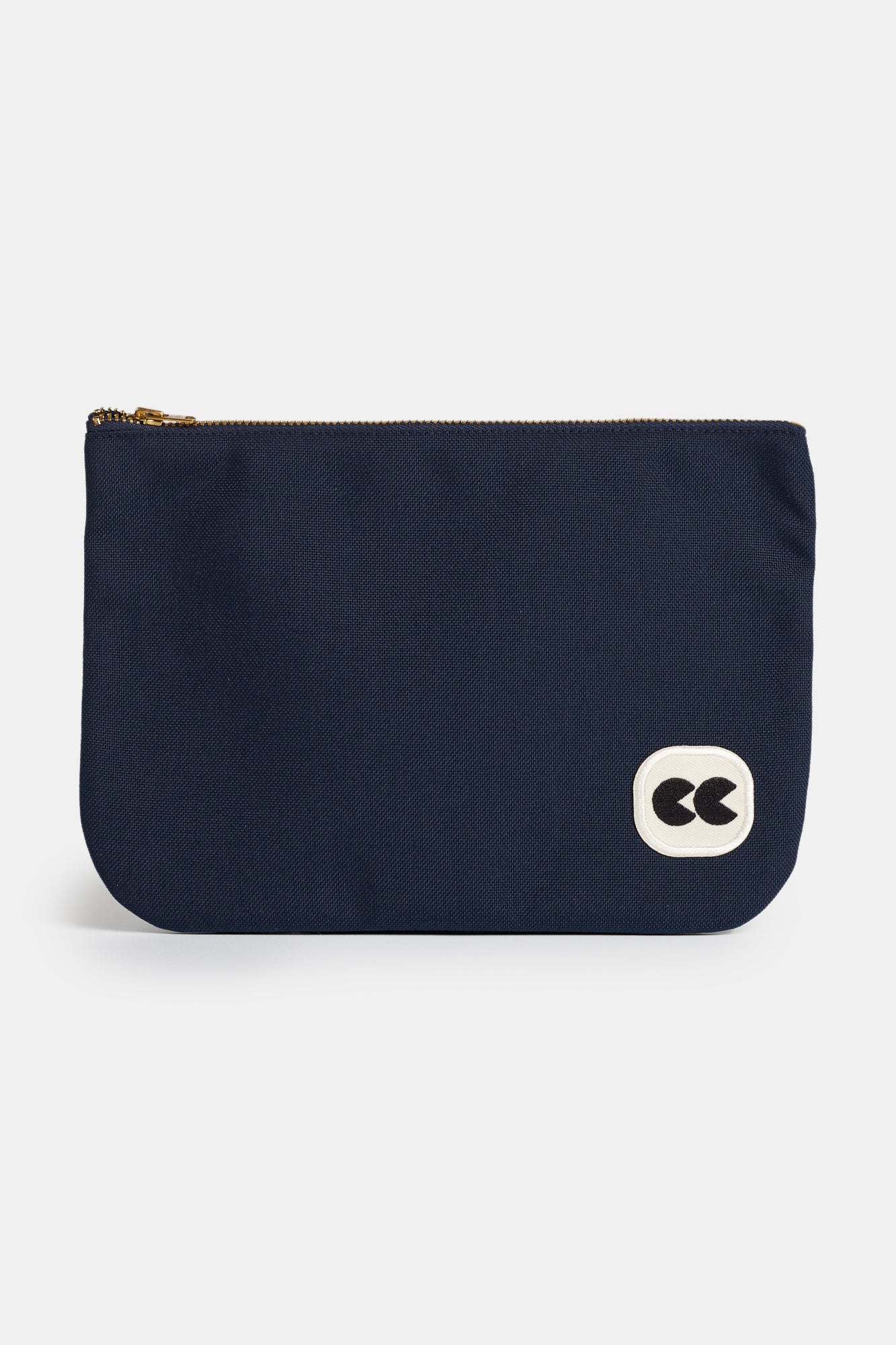 Front of small sized navy zip pouch. White badge with black CC logo in the bottom right hand corner