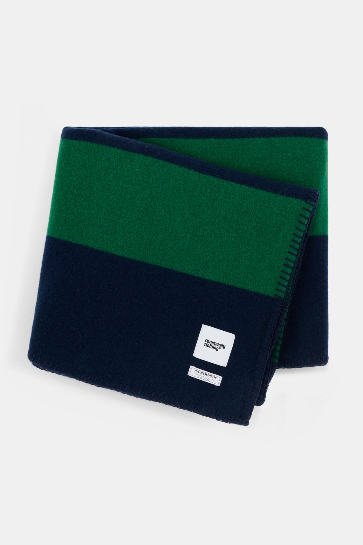 Flatlay of bottle and navy stripe blanket folded up showing Community Clothing  woven logo.