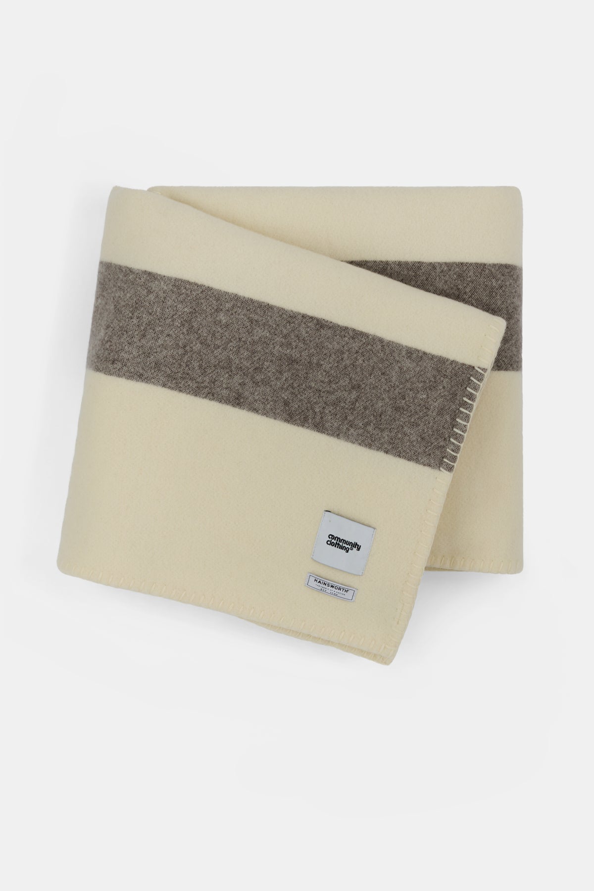Ecru, dark brown and tan stripe blanket  folded up showing Community Clothing  and Hainsworth woven logo 