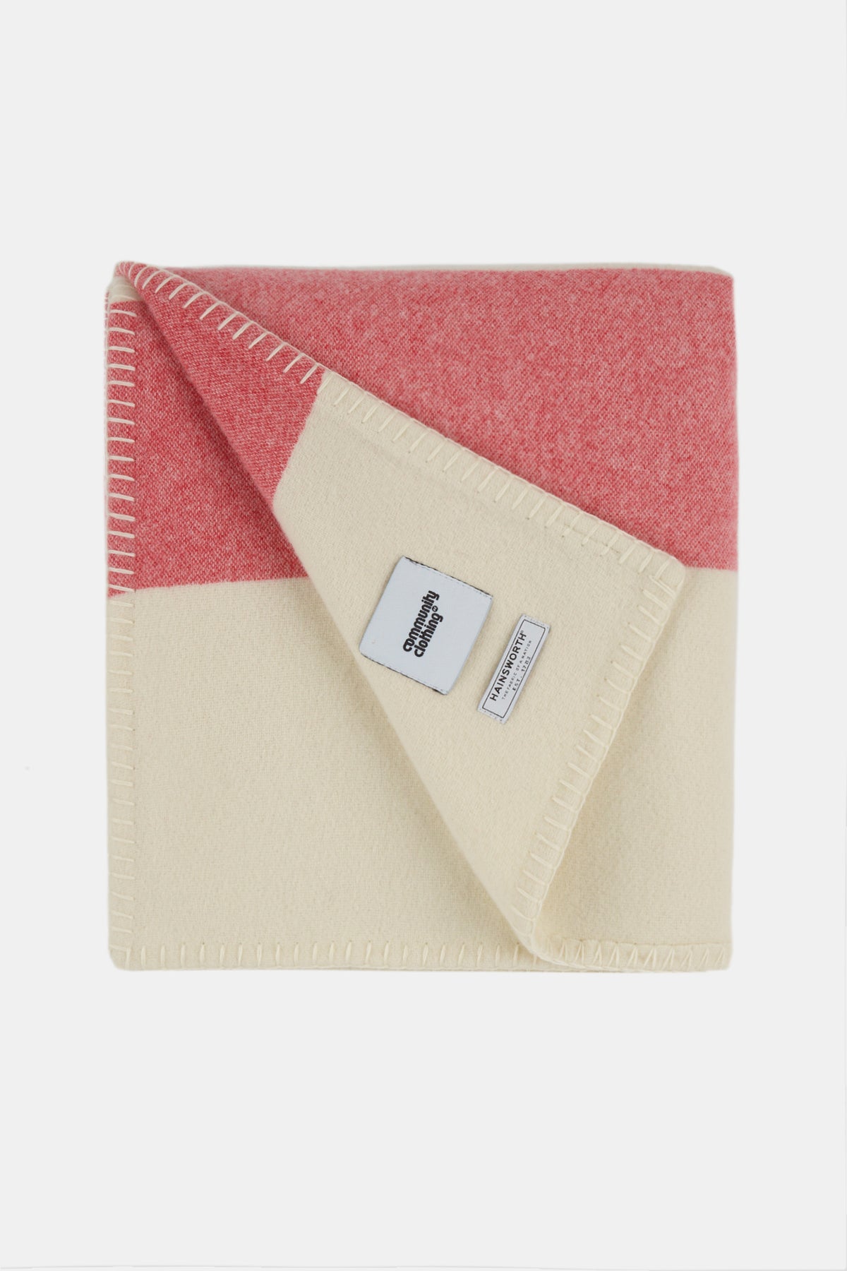 Image of folded pure wool striped blanket in ecru red navy showing Community Clothing and A W Hainsworth logo badges. Blanket stitch detail.