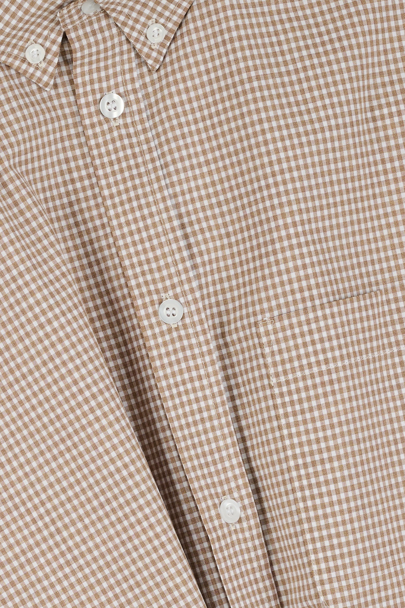 Close-up of a brown and white checkered shirt with buttons.