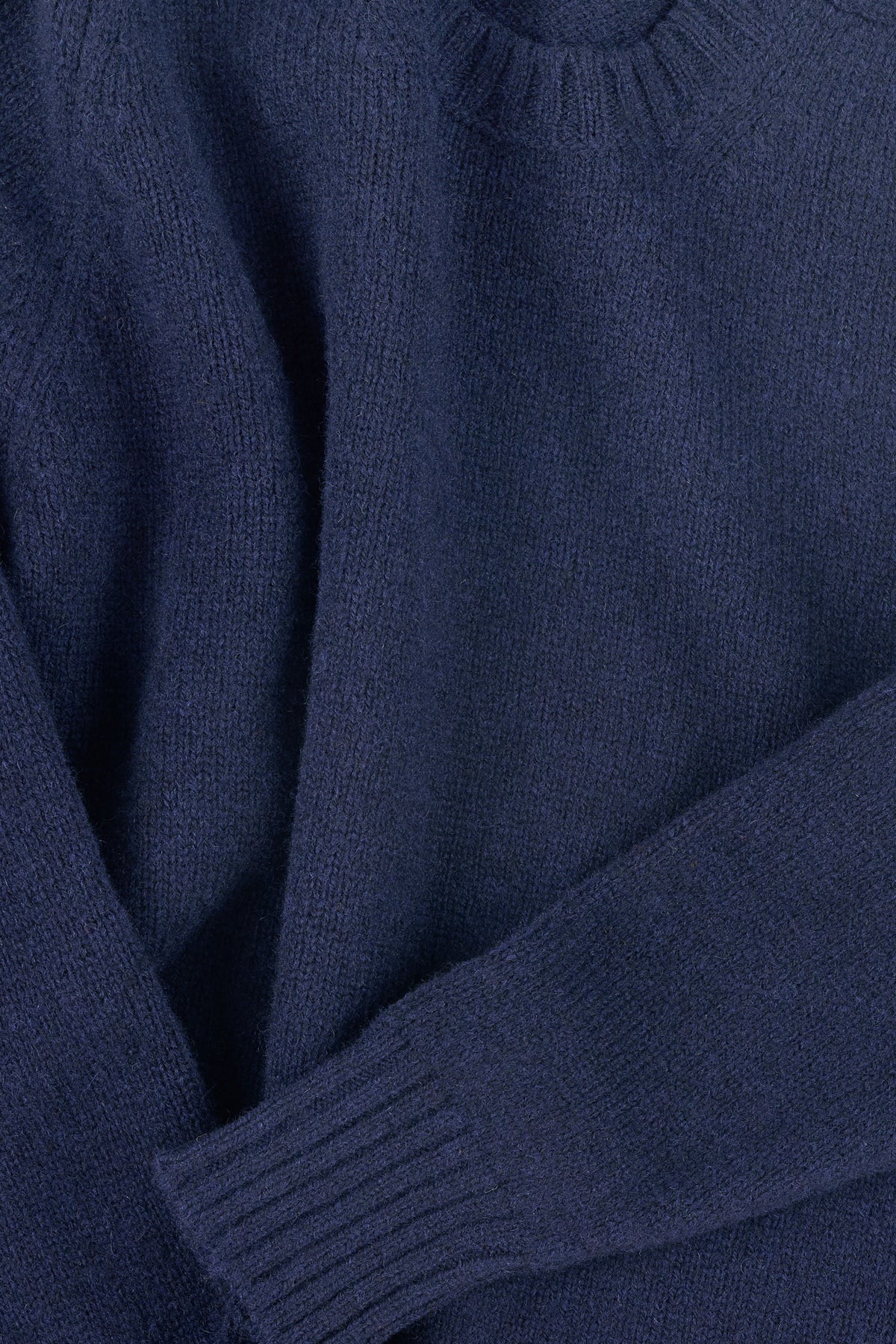 Close-up of a navy blue sweater with ribbed cuff and hem