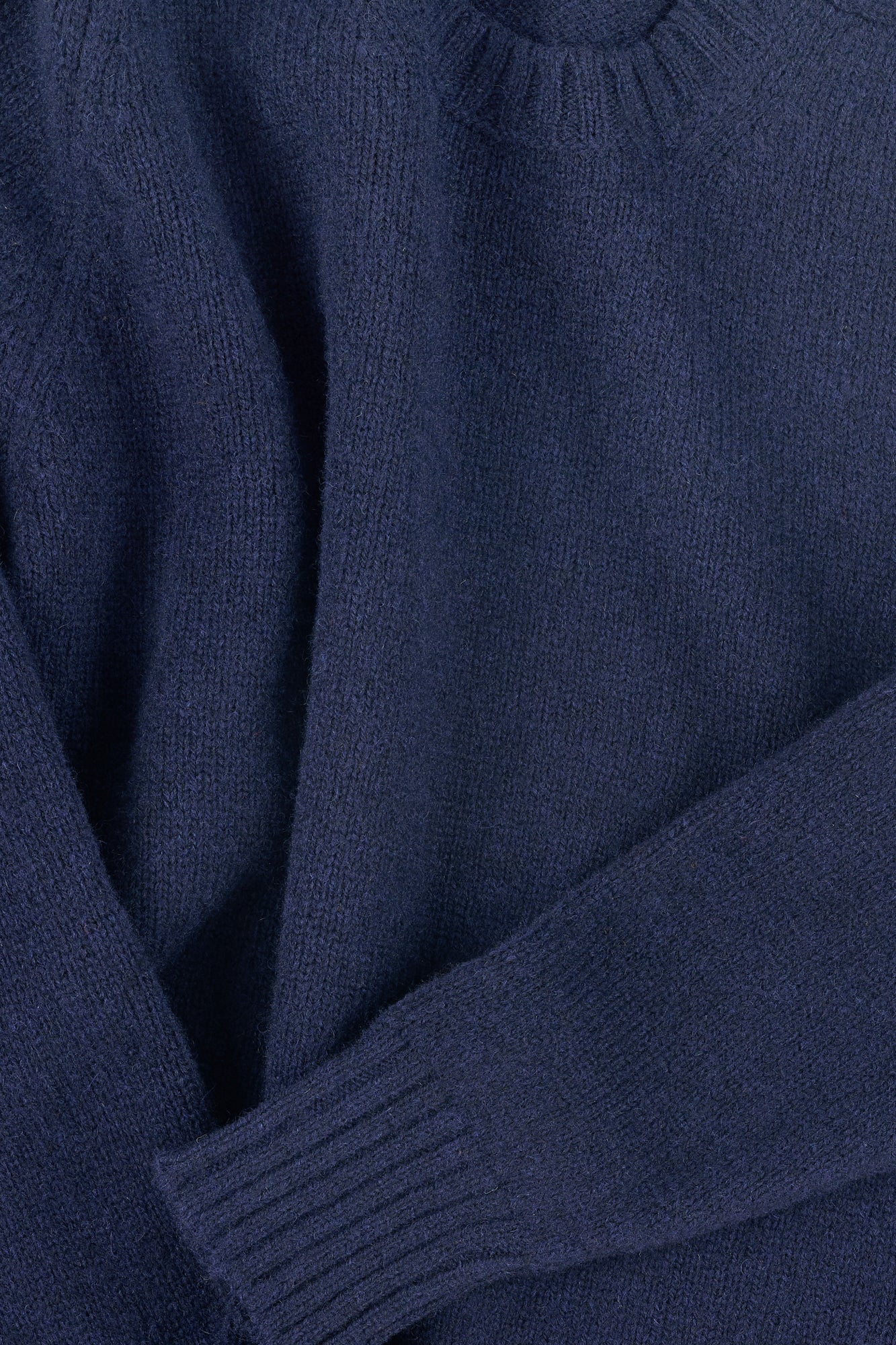 Close up of navy shetland knit sweatshirt with ribbed neckline and cuff.