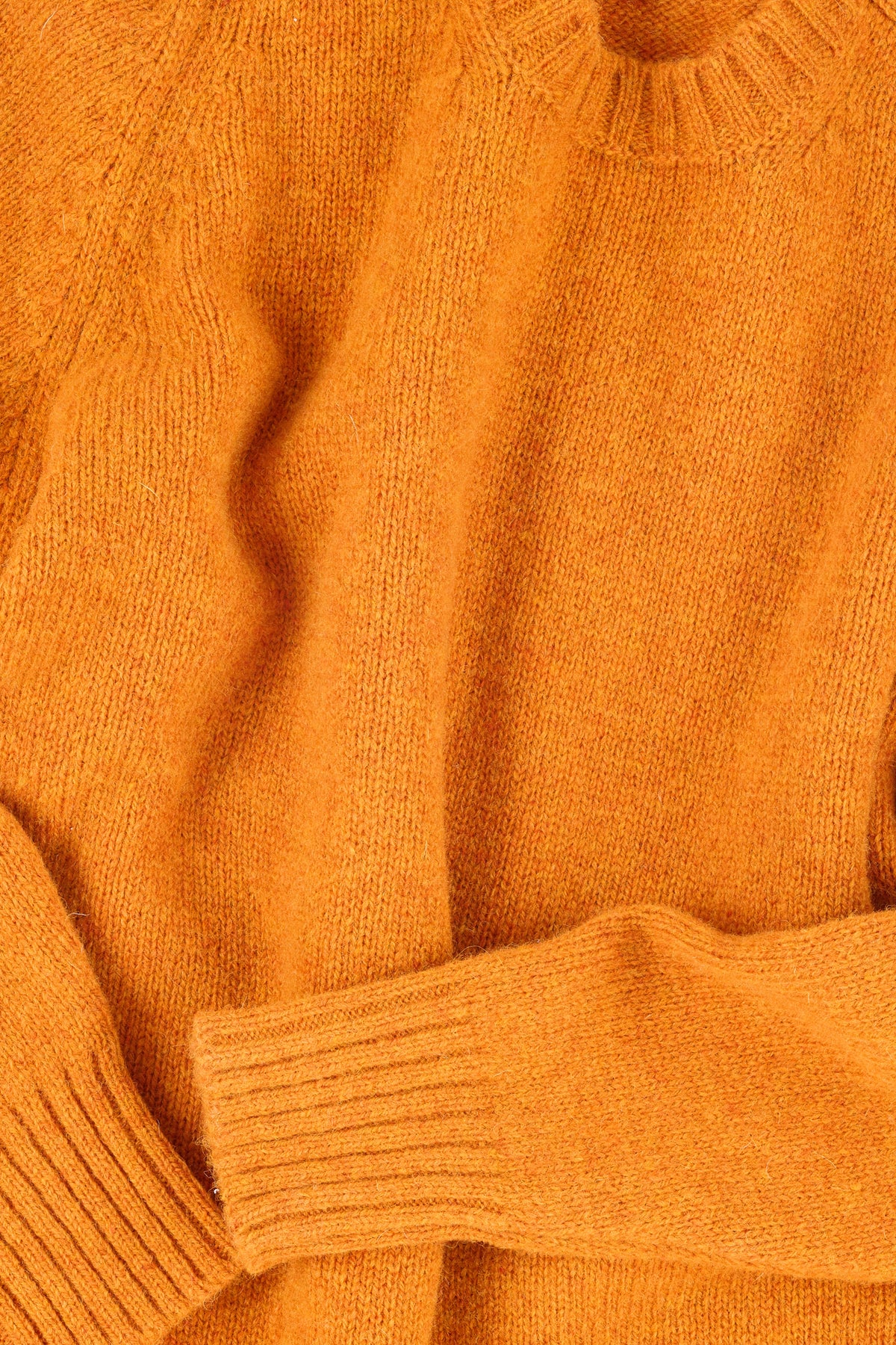 Close up of the ribbed collar and cuff of an orange sweater
