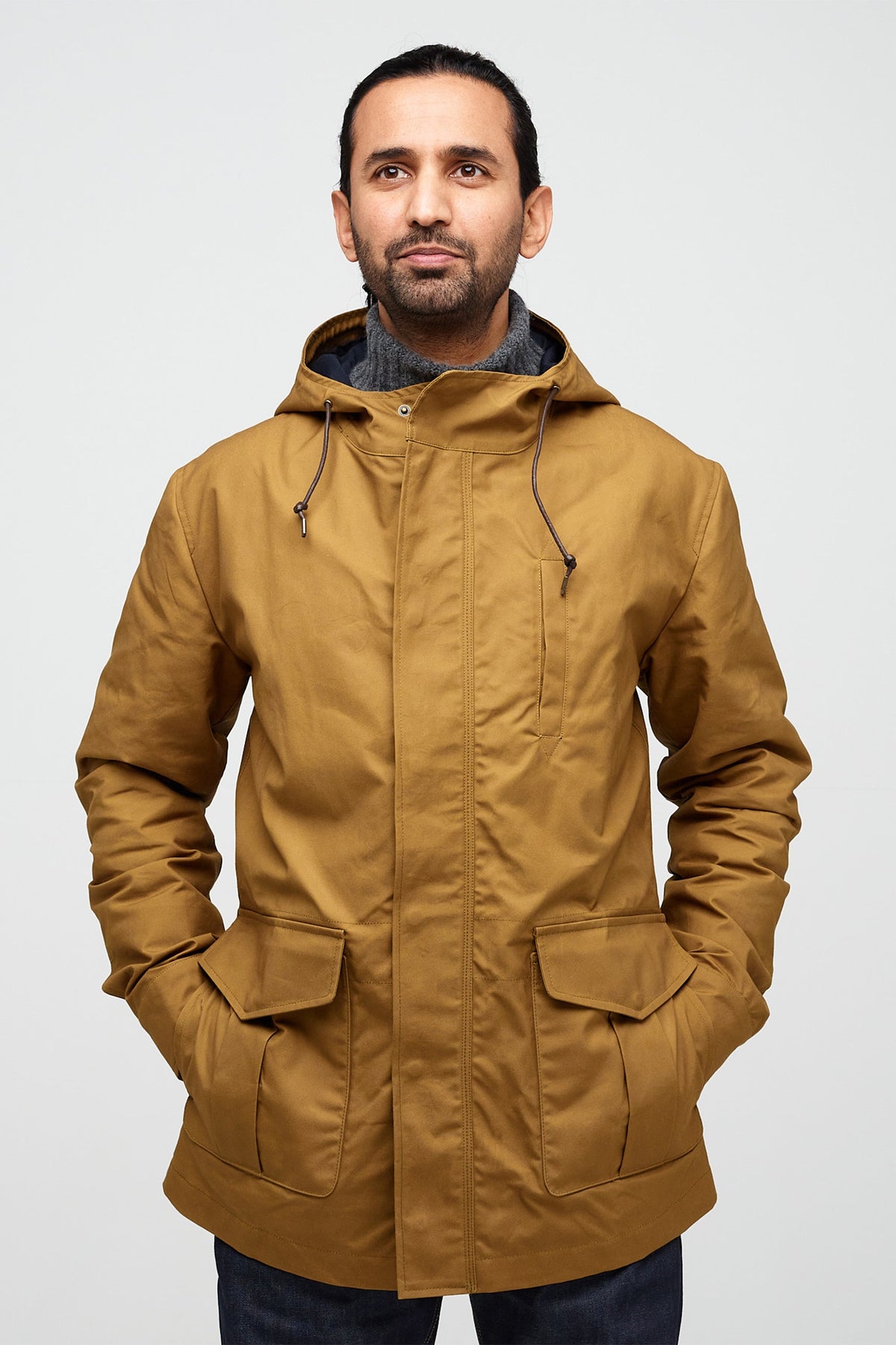 male wearing mountain parka in tan with hands in front pockets 